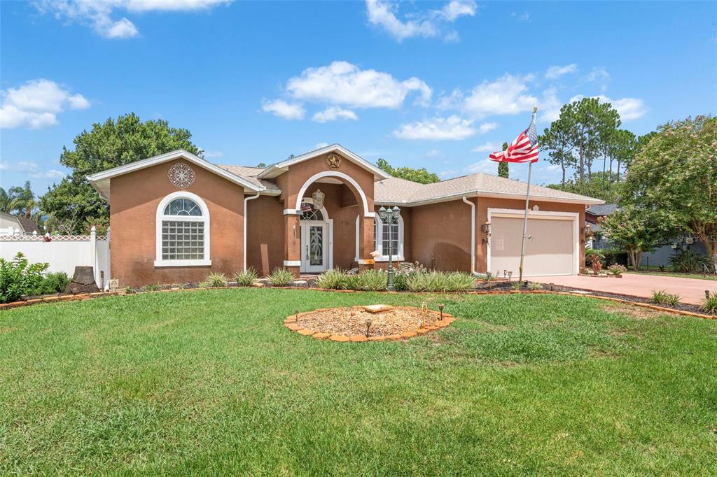 A single-story stucco house with a two-car garage, arched entryway, and a front lawn — 52 BUTTONWORTH DRIVE, PALM COAST, FL