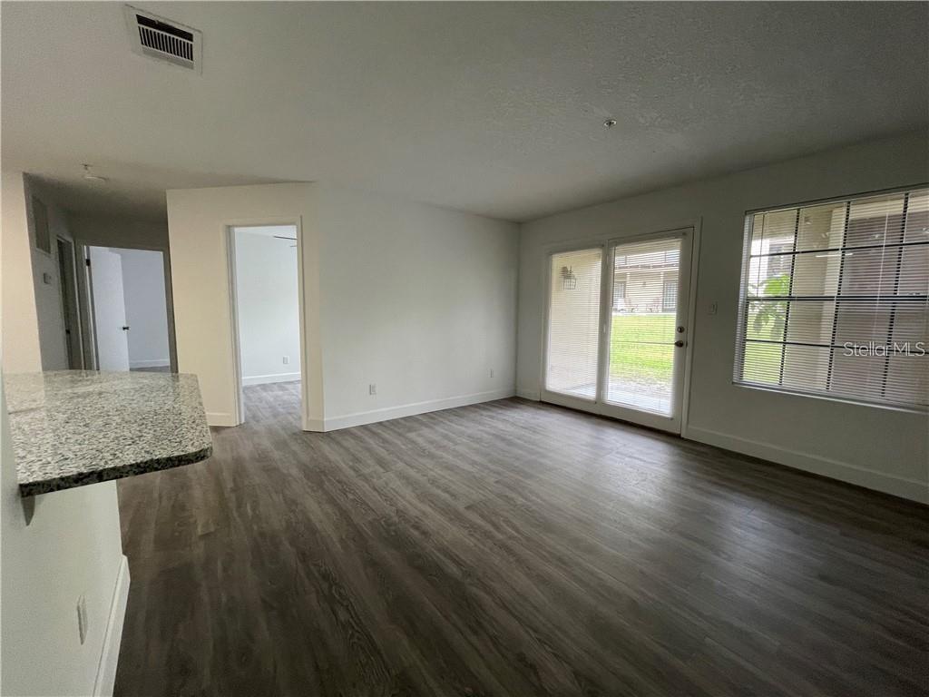 An interior view of a living room with wood-look flooring, sliding glass doors, and granite countertops — 232 AFTON SQUARE UNIT 112, ALTAMONTE SPRINGS, FL