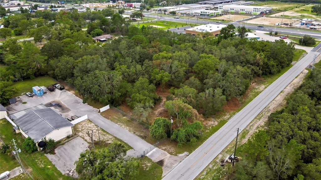 An aerial view shows a wooded lot situated between a commercial building and a road — 0 OLD SHADY HILLS ROAD, SPRING HILL, FL