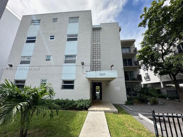 A multi-story apartment building features a light-colored facade with a central entrance and balconies — 1337 NW 1st St # 14, Miami FL 33125, MIAMI, FL