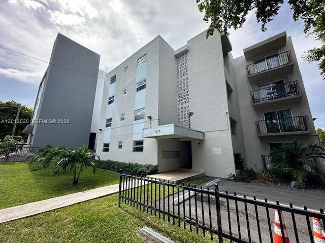 A multi-story apartment building features a grey facade, balconies, and a small entrance canopy — 1337 NW 1st St # 14, Miami FL 33125, MIAMI, FL