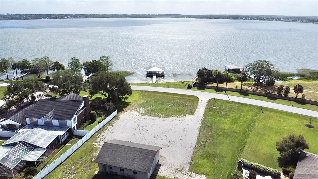 An aerial view shows a vacant lot situated between a house and a lakefront — 3155 LAKESHORE DRIVE, MOUNT DORA, FL