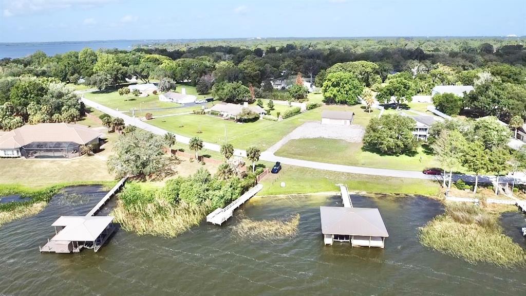 An aerial view shows two boat docks extending into a lake from a grassy shoreline — 3155 LAKESHORE DRIVE, MOUNT DORA, FL