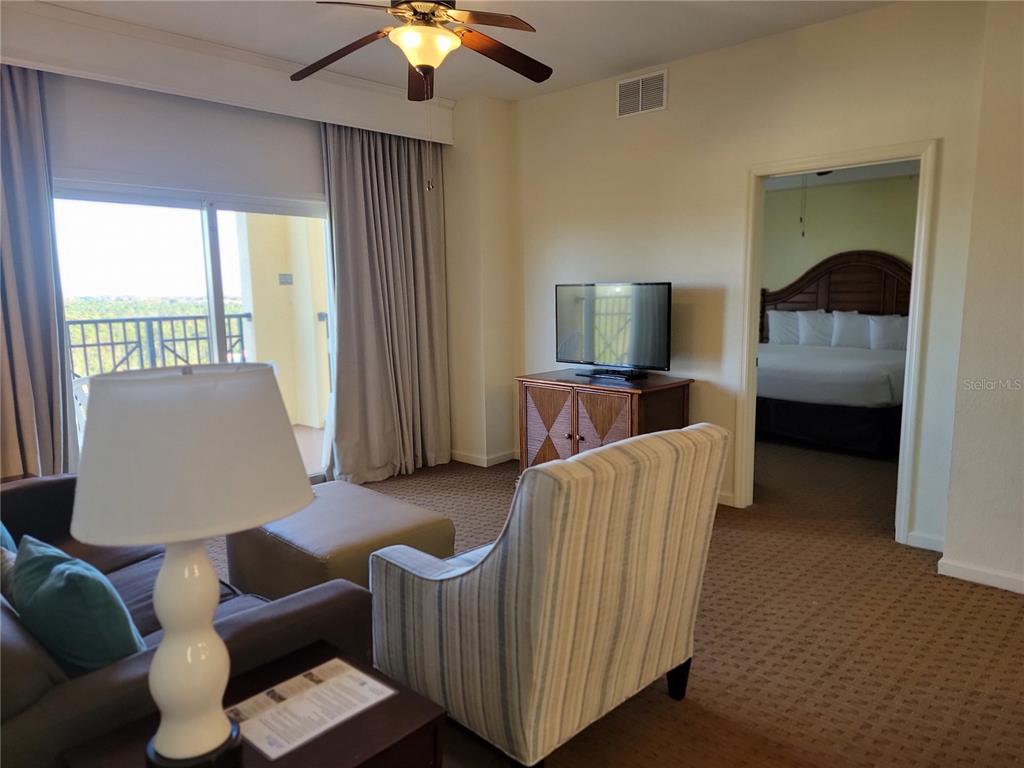An open-concept living and dining area features a brown sofa, striped armchair, and kitchen — 8101 RESORT VILLAGE DRIVE UNIT 31212, ORLANDO, FL