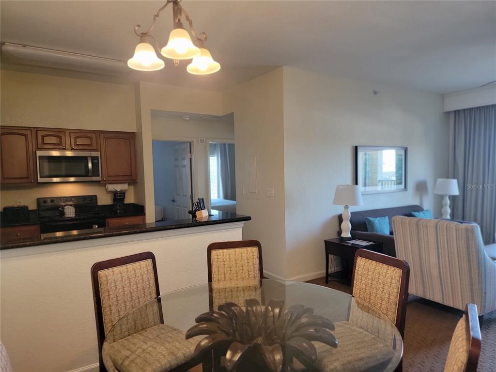 A living room with a striped armchair, a television, and a view of a balcony — 8101 RESORT VILLAGE DRIVE UNIT 31212, ORLANDO, FL