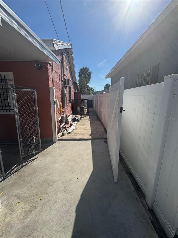 A narrow concrete walkway sits between a red exterior wall and a white vinyl fence — 2312 W LA SALLE STREET, TAMPA, FL