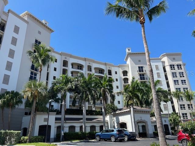 A multi-story residential building features white stucco walls, balconies, and surrounding palm trees — 3313 SUNSET KEY CIRCLE UNIT 203, PUNTA GORDA, FL