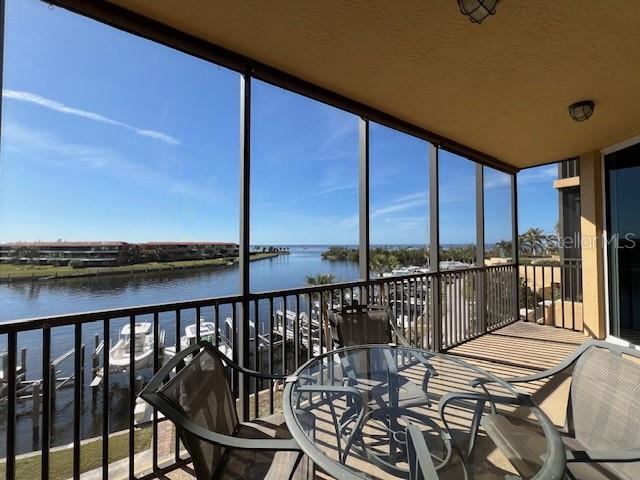A screened-in balcony overlooks a canal with docked boats and distant waterfront buildings — 3313 SUNSET KEY CIRCLE UNIT 203, PUNTA GORDA, FL