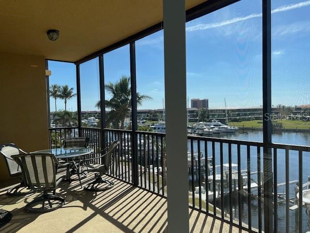A screened-in balcony overlooks a marina with several boats docked in the water — 3313 SUNSET KEY CIRCLE UNIT 203, PUNTA GORDA, FL