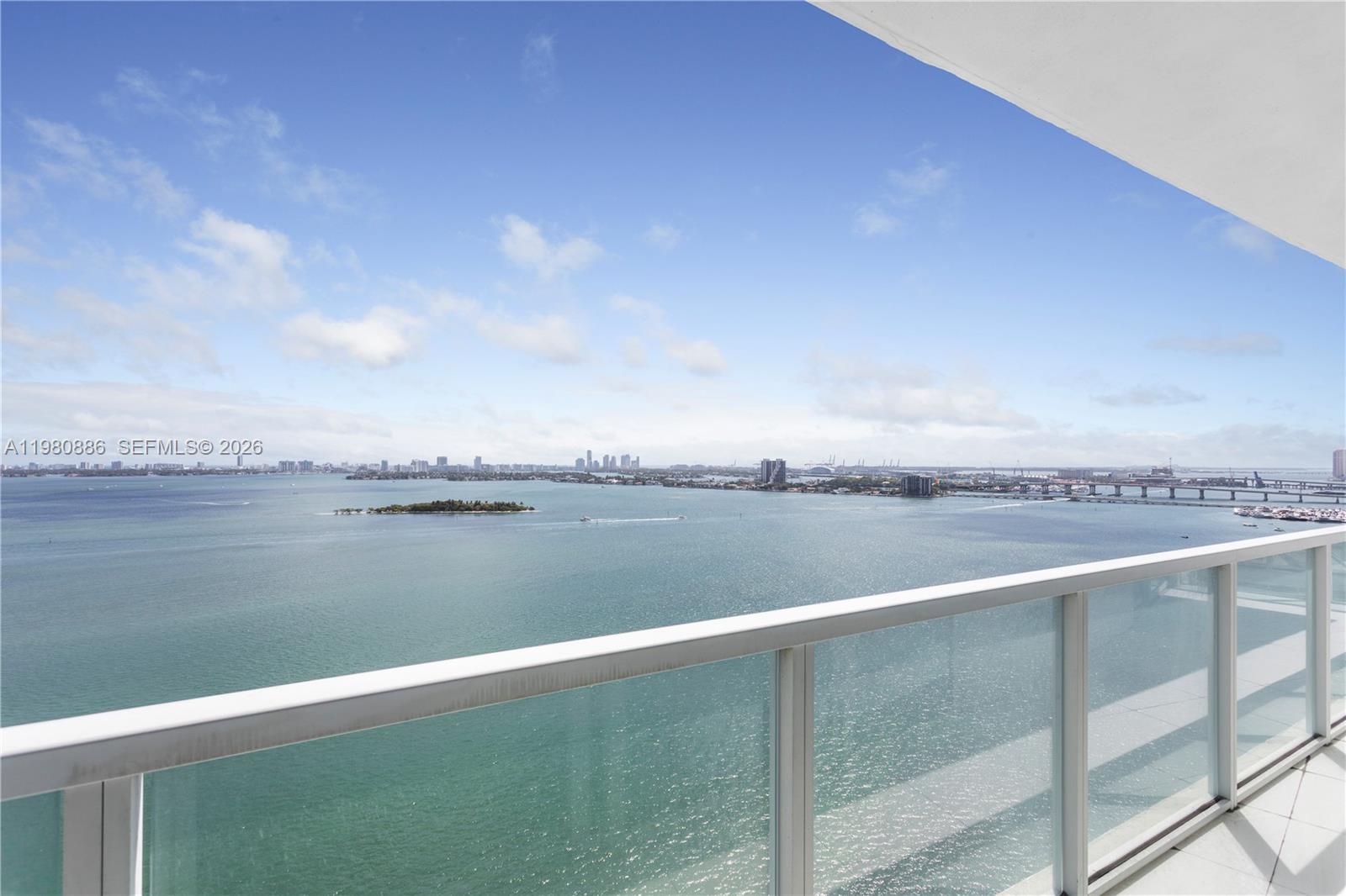 A high-rise balcony overlooks a wide bay with a distant city skyline and bridge — 665 NE 25th St # 2102, Miami FL 33137, MIAMI, FL
