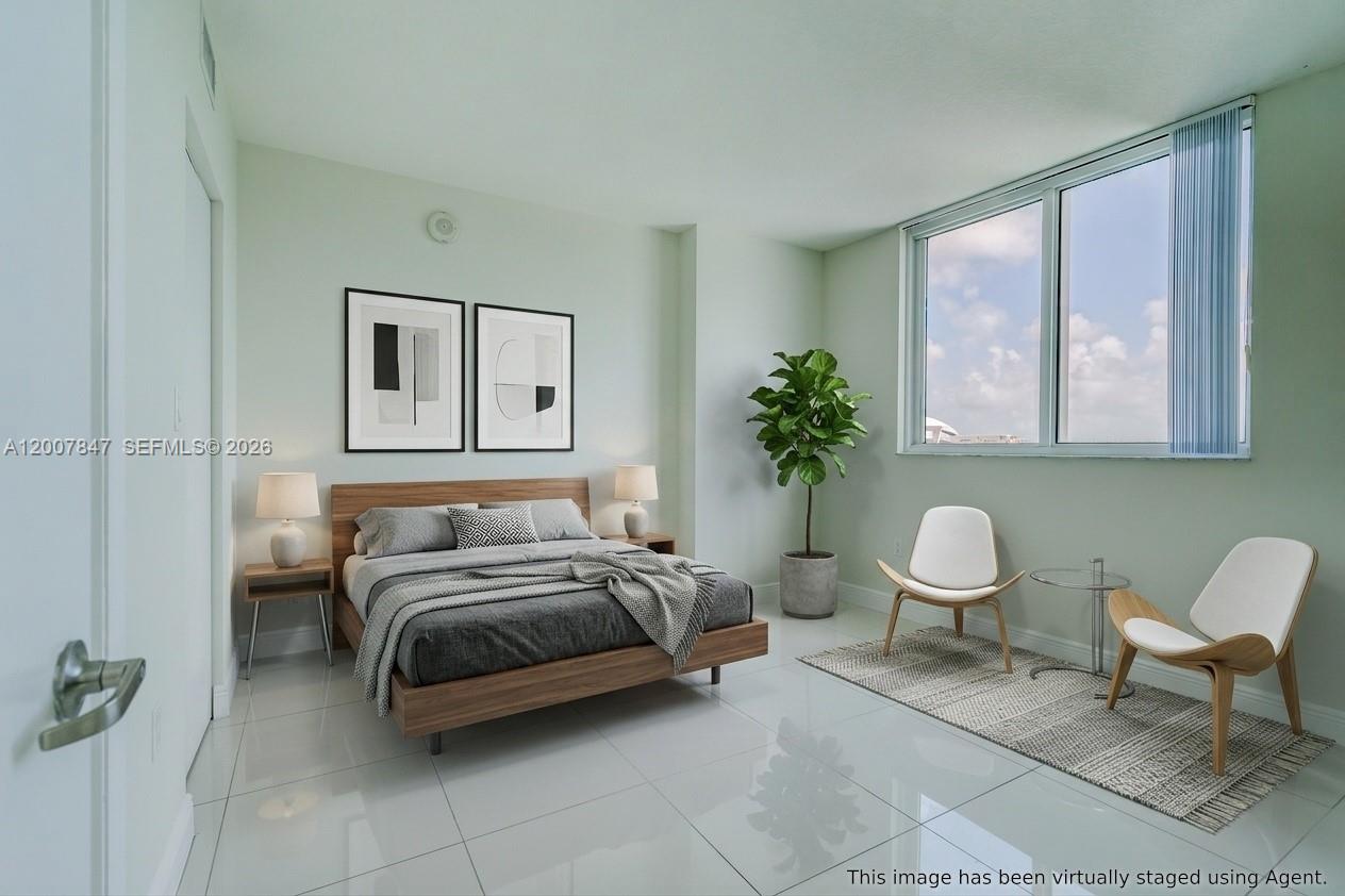 This bedroom features a platform bed, two chairs, and large windows with light-colored tile flooring — 1871 NW S River Dr # 802, Miami FL 33125, MIAMI, FL