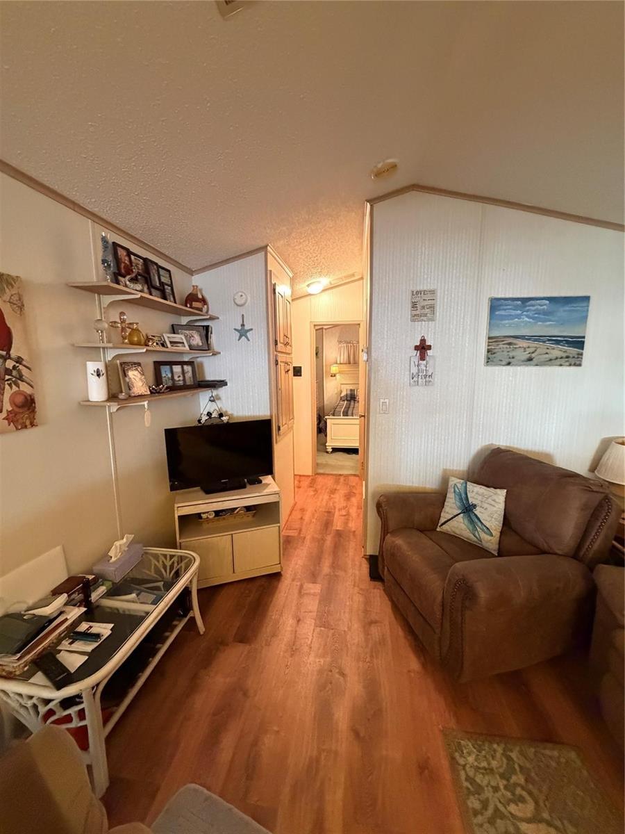 A living room with wood-look flooring, a television on a stand, and a brown armchair — 6444 SE 51st Lane, Okeechobee FL 34974, OKEECHOBEE, FL