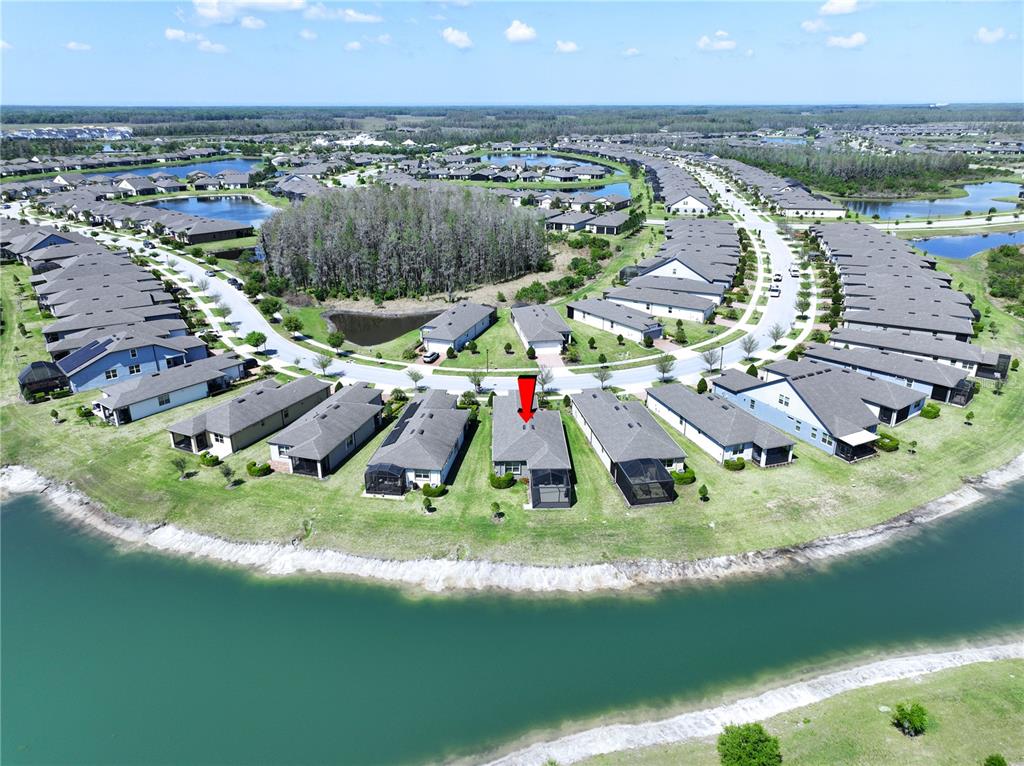 An aerial view shows a residential neighborhood with a red arrow pointing to a house — 19537 SHIP WHEEL WAY, LAND O LAKES, FL