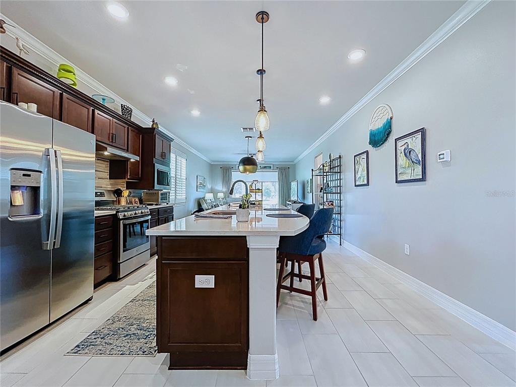 A kitchen features dark wood cabinetry, a large white island, and stainless steel appliances — 19537 SHIP WHEEL WAY, LAND O LAKES, FL