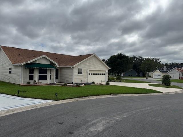 A single-story house with light siding, a brown roof, and a green awning over windows — 903 RAMOS DRIVE, THE VILLAGES, FL