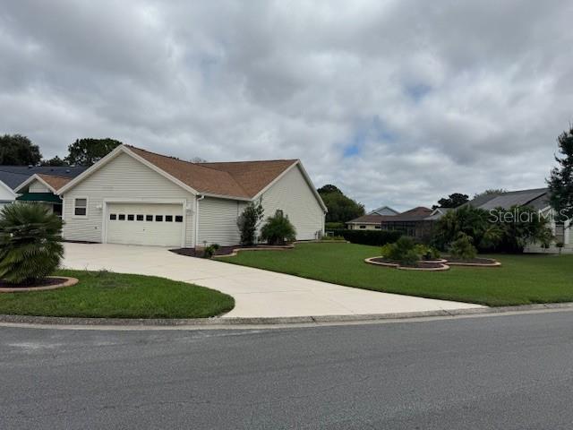 A single-story house with light siding, a brown roof, and a concrete driveway — 903 RAMOS DRIVE, THE VILLAGES, FL