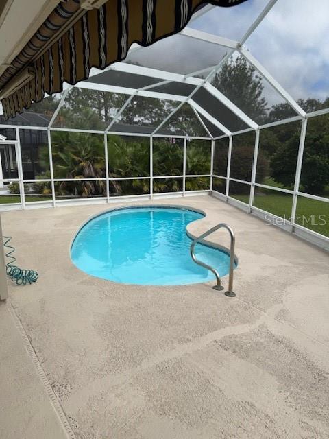 A kidney-shaped swimming pool sits inside a screened-in lanai with a concrete deck — 903 RAMOS DRIVE, THE VILLAGES, FL