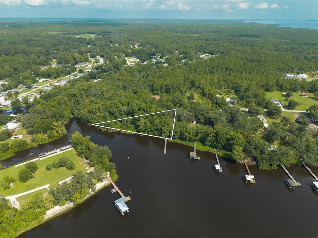 A grassy, wooded lot features large oak trees draped in Spanish moss and utility lines — 102 CEDAR CREEK ROAD, PALATKA, FL