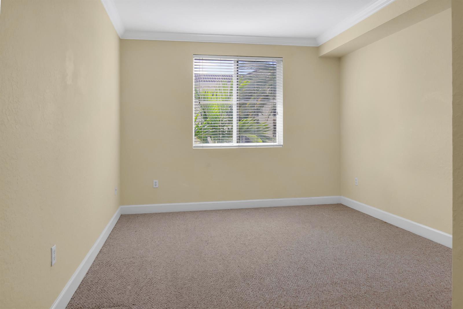 An empty bedroom with beige walls, tan carpet, white trim, and a window with blinds — 1690 Renaissance Commons Boulevard # 1103, Boynton Beach FL 33426, BOYNTON BEACH, FL