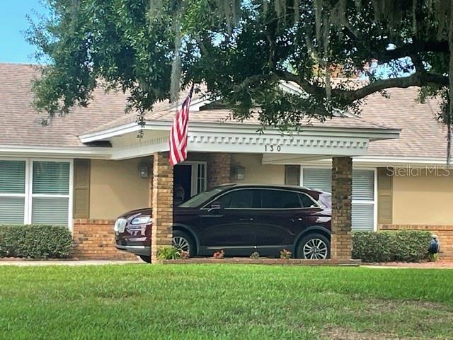 A dark SUV is parked under the covered entryway of a single-story house — 130 SPRINGWOOD TRAIL, ALTAMONTE SPRINGS, FL