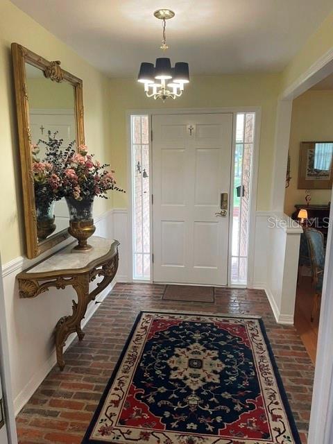 An entryway features a brick floor, a gold-framed mirror, a console table, and a chandelier — 130 SPRINGWOOD TRAIL, ALTAMONTE SPRINGS, FL