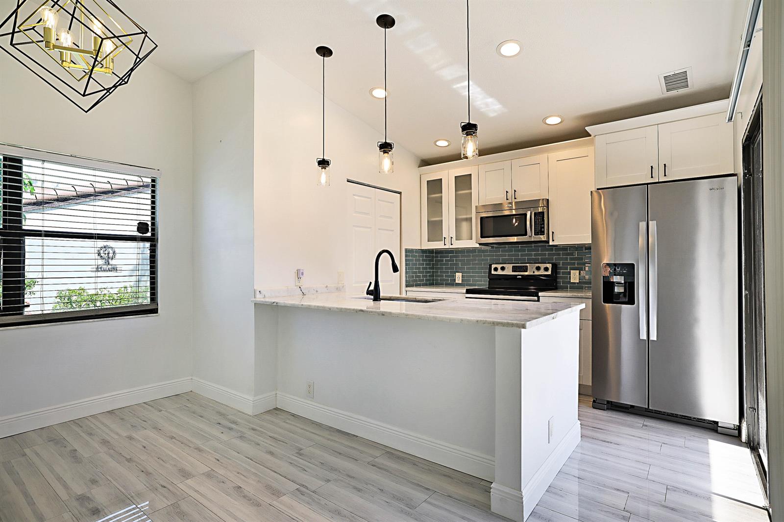 A kitchen features white cabinets, a marble-topped island with a black faucet, and stainless appliances — 22354 Pineapple Walk Drive, Boca Raton FL 33433, BOCA RATON, FL