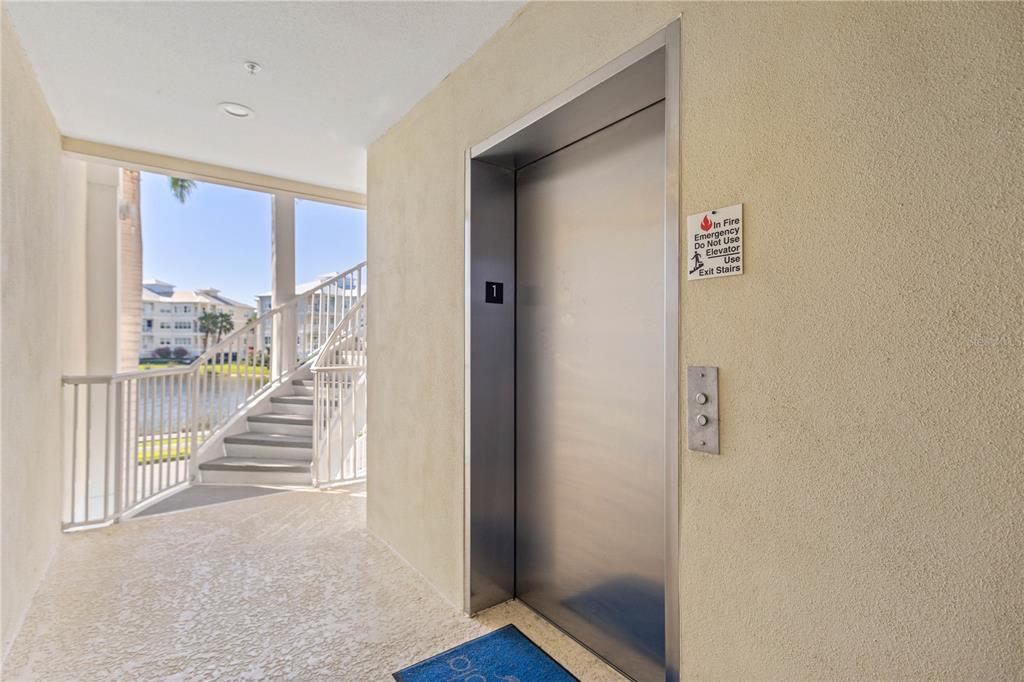 An elevator with a fire safety sign is located in an outdoor hallway near stairs — 3431 79TH STREET CIRCLE W UNIT 101, BRADENTON, FL
