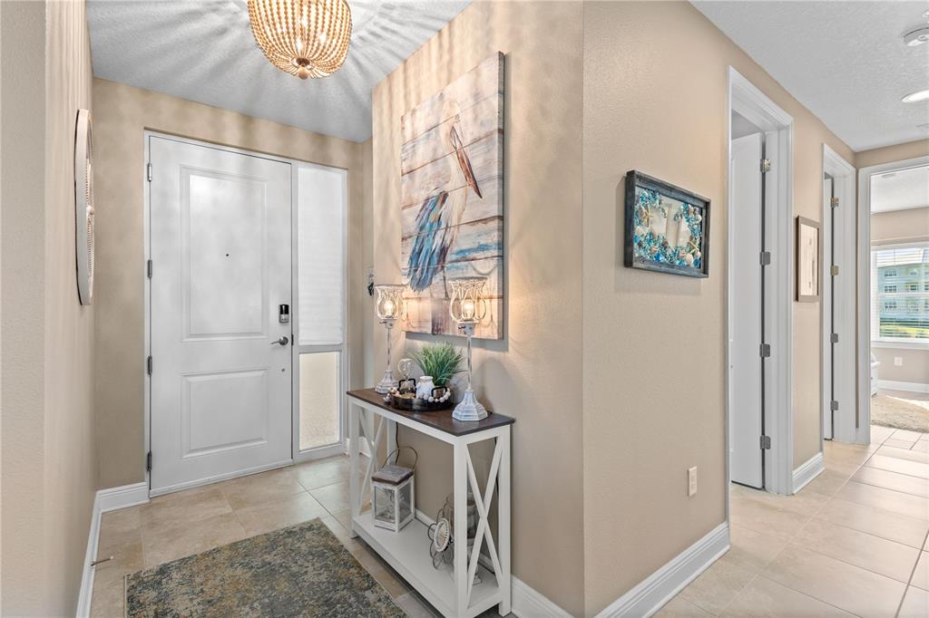 An entryway features a white door, a console table with decor, and a pelican wall art — 3431 79TH STREET CIRCLE W UNIT 101, BRADENTON, FL