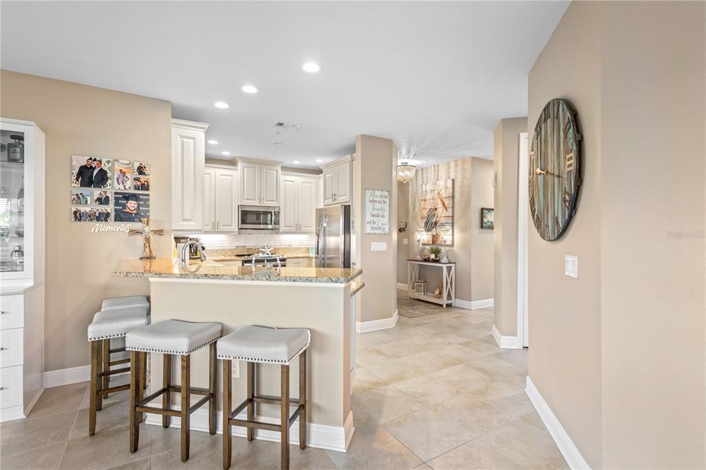 A kitchen with white cabinets, granite countertops, and a breakfast bar with three stools — 3431 79TH STREET CIRCLE W UNIT 101, BRADENTON, FL