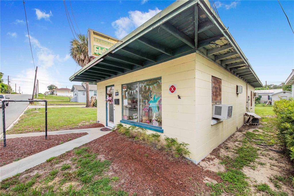 A single-story, light-yellow concrete block commercial building with a flat roof and large display windows — 29 N 10TH STREET, HAINES CITY, FL