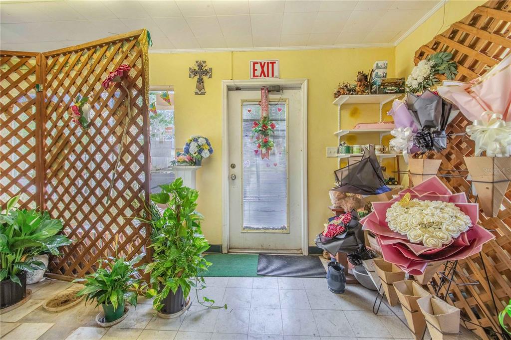 A floral shop interior features a lattice screen, potted plants, and bouquets near an exit door — 29 N 10TH STREET, HAINES CITY, FL
