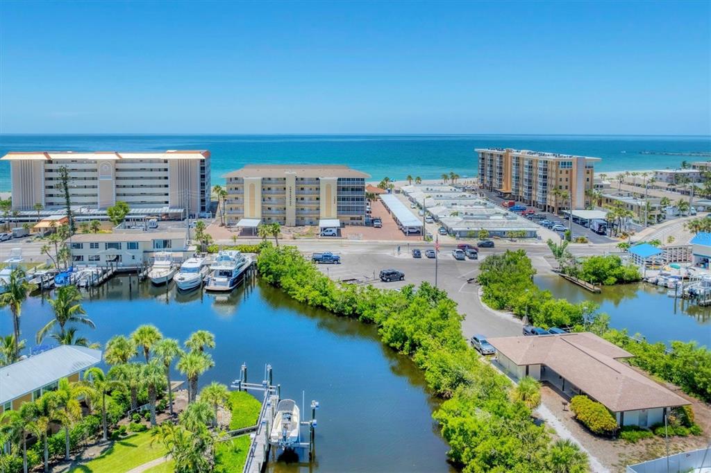 An aerial view shows a coastal area with apartment buildings, a marina, and a canal — 1200 TARPON CENTER DRIVE UNIT 306, VENICE, FL