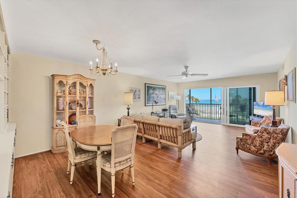 A dining and living area with wood floors, a chandelier, and a balcony overlooking the ocean — 1200 TARPON CENTER DRIVE UNIT 306, VENICE, FL