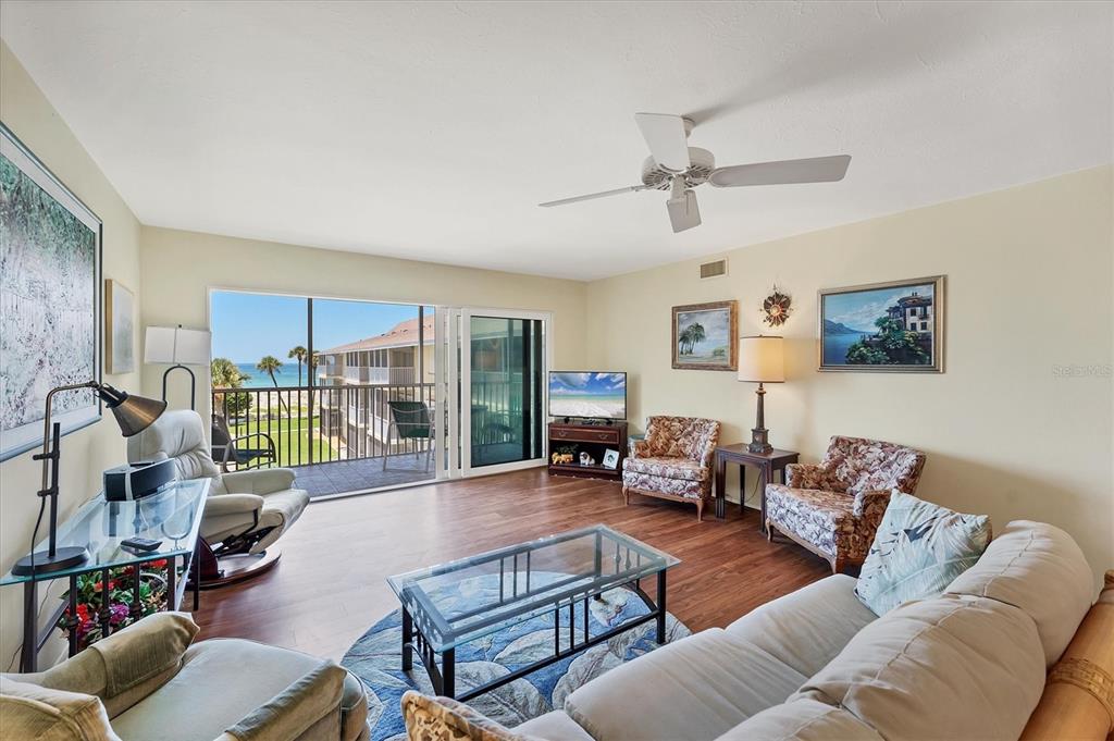 A living room with wood-look flooring, a ceiling fan, and a balcony overlooking the ocean — 1200 TARPON CENTER DRIVE UNIT 306, VENICE, FL