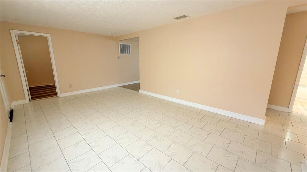 An empty room with light-colored tile flooring, beige walls, and two doorways — 4102 HIGHLAND LOOP, NEW PORT RICHEY, FL