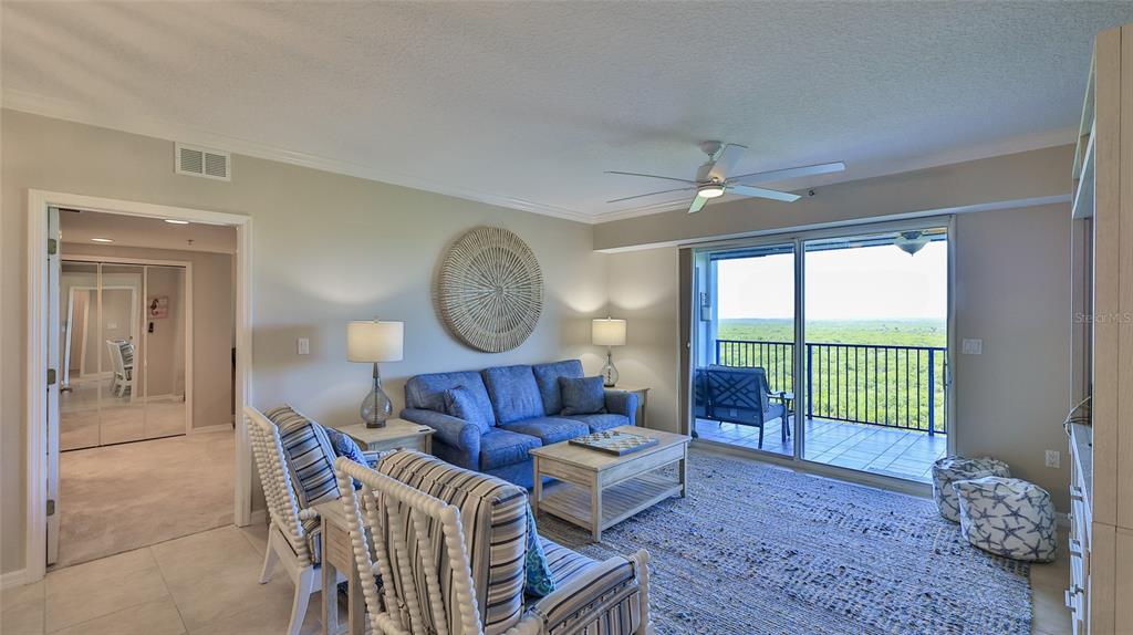 A living room features a blue sofa, striped chairs, a coffee table, and a balcony view — 5300 S ATLANTIC AVENUE UNIT 16-602, NEW SMYRNA BEACH, FL