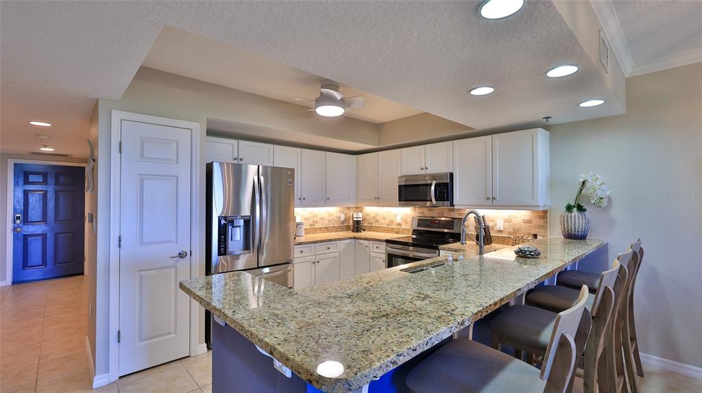 A kitchen features white cabinets, granite countertops, stainless steel appliances, and a breakfast bar — 5300 S ATLANTIC AVENUE UNIT 16-602, NEW SMYRNA BEACH, FL