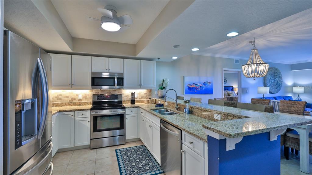 A kitchen features white cabinets, granite countertops, stainless steel appliances, and a blue breakfast bar — 5300 S ATLANTIC AVENUE UNIT 16-602, NEW SMYRNA BEACH, FL
