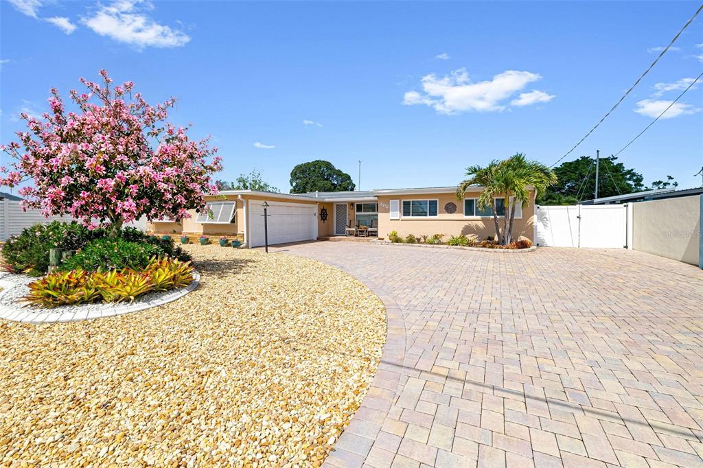 A single-story house with a paved driveway, a blooming tree, and a palm tree — 302 BRYN MAWR ISLAND, BRADENTON, FL