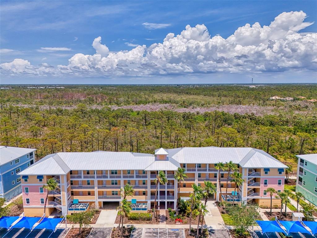 An aerial view shows a multi-story apartment building with a metal roof and palm trees — 8409 PLACIDA ROAD UNIT 206, PLACIDA, FL