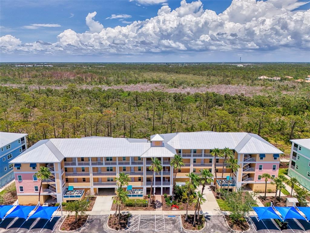An aerial view shows a multi-story apartment building with a metal roof and parking shades — 8409 PLACIDA ROAD UNIT 206, PLACIDA, FL