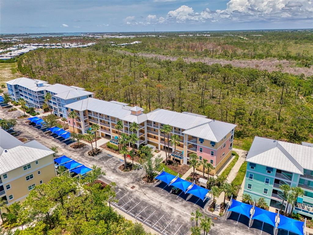 An aerial view shows multi-story apartment buildings with metal roofs and blue parking shades — 8409 PLACIDA ROAD UNIT 206, PLACIDA, FL
