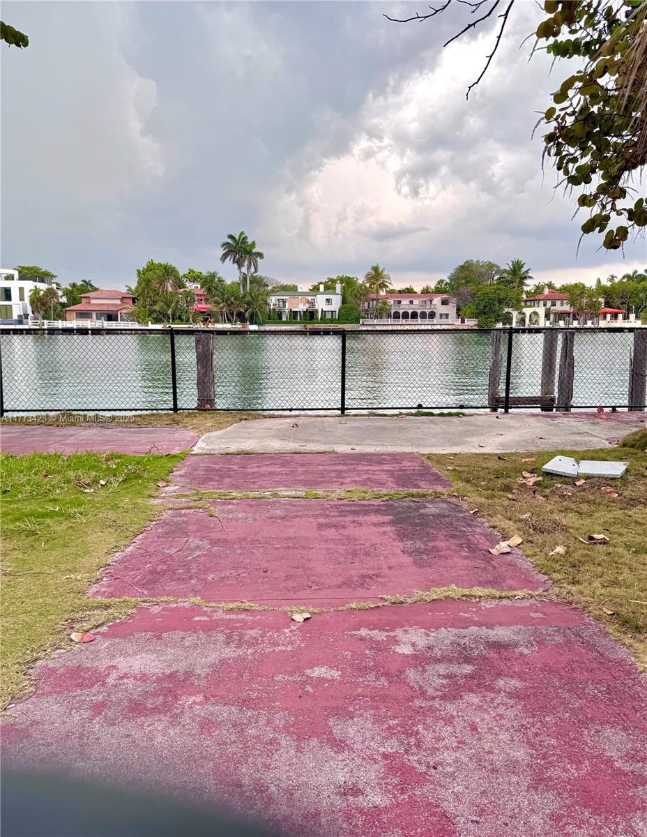 A paved path leads to a chain-link fence overlooking a canal with waterfront homes — 5255 Collins Ave Boat Slip E, Miami Beach FL 33140, MIAMI BEACH, FL