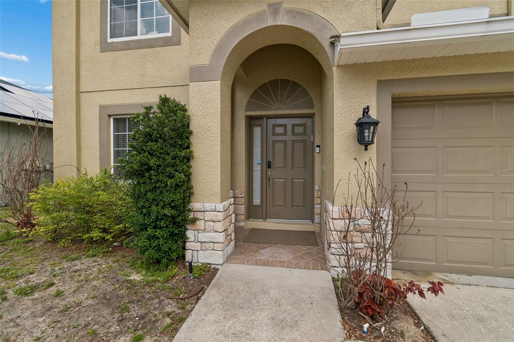 The exterior of a house features a tan stucco facade, stone accents, and a front entrance — 2829 PANKAW LANE, VALRICO, FL