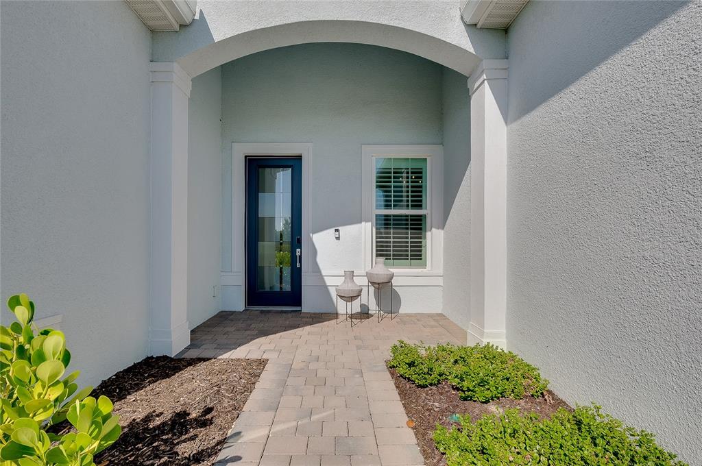 A paved walkway leads to a covered entryway with a dark door and a window — 10105 BEACHWALK DRIVE, ENGLEWOOD, FL