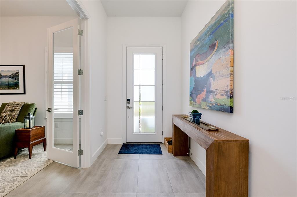 An entryway features a white front door, a wooden console table, and abstract wall art — 10105 BEACHWALK DRIVE, ENGLEWOOD, FL