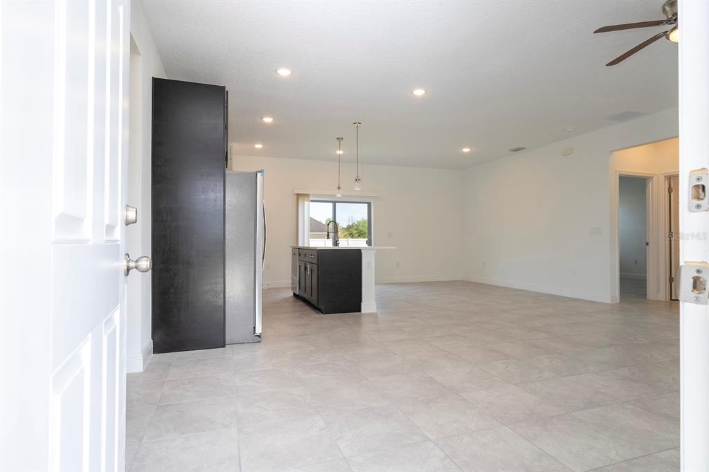 An open-concept kitchen and living area features dark cabinetry, a kitchen island, and tile flooring — 15026 SW 24TH CIRCLE, OCALA, FL