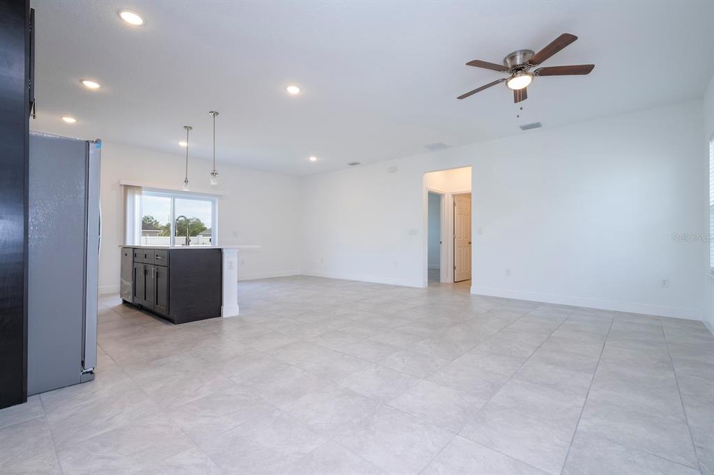 An open-concept kitchen and living area features light tile flooring, white walls, and a ceiling fan — 15026 SW 24TH CIRCLE, OCALA, FL