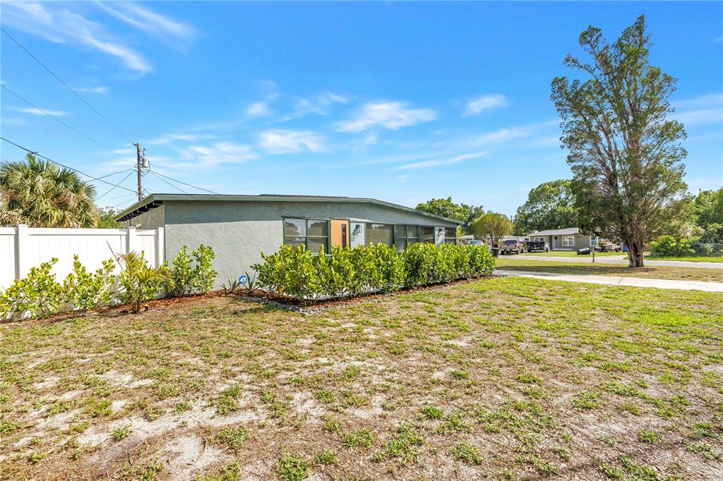 A single-story house with a gray exterior, a white fence, and a large tree — 7599 MEADOWLAWN DRIVE N, ST PETERSBURG, FL