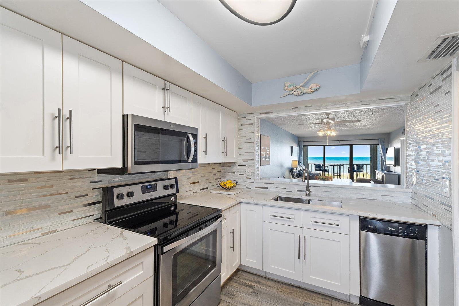 A modern kitchen features white cabinets, stainless steel appliances, and a view of the ocean — 10310 S Ocean Drive # 205, Jensen Beach FL 34957, JENSEN BEACH, FL